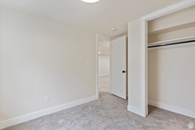 unfurnished bedroom featuring light carpet and a closet