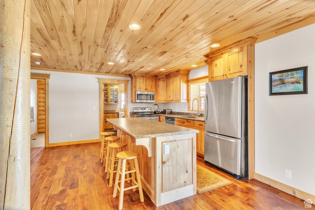 kitchen featuring a breakfast bar, sink, light hardwood / wood-style floors, appliances with stainless steel finishes, and a kitchen island