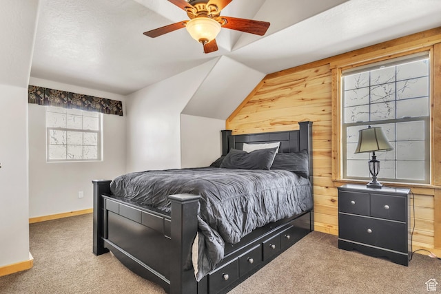 carpeted bedroom featuring ceiling fan, lofted ceiling, and wood walls