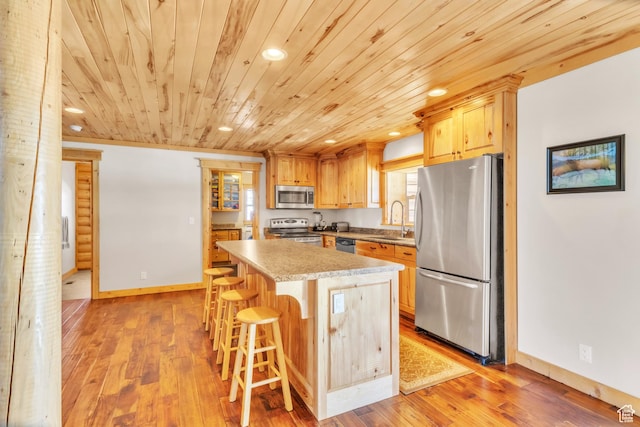 kitchen featuring a center island, sink, stainless steel appliances, light hardwood / wood-style flooring, and a breakfast bar