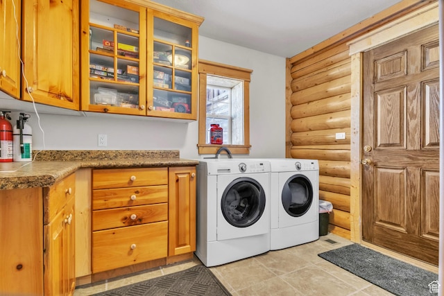 laundry room with cabinets, independent washer and dryer, and rustic walls