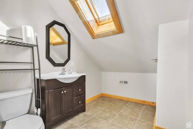 bathroom featuring vaulted ceiling with skylight, vanity, and toilet