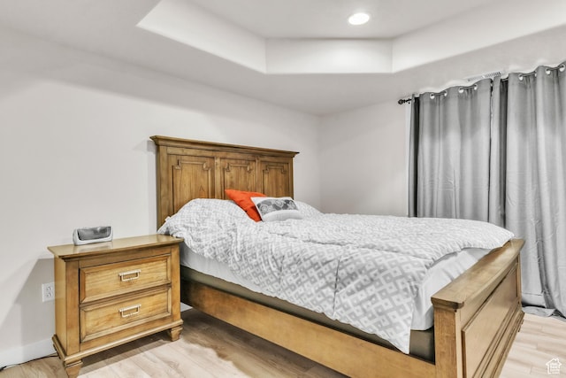 bedroom featuring light wood-type flooring and a tray ceiling