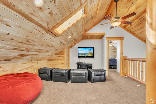 home theater featuring vaulted ceiling with skylight, wood ceiling, ceiling fan, wooden walls, and carpet floors