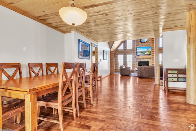 dining space featuring a fireplace, hardwood / wood-style floors, vaulted ceiling, and wood ceiling