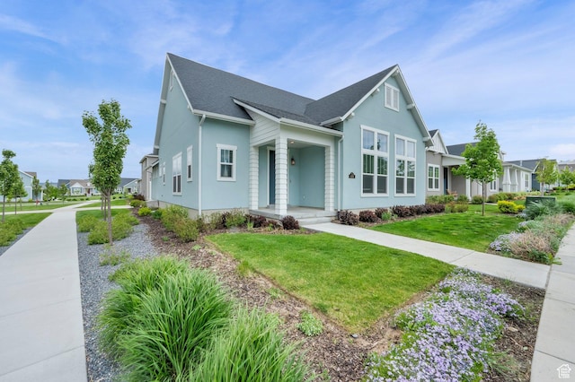 view of front facade featuring a shingled roof, a front lawn, stucco siding, and a residential view