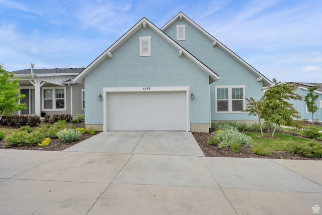 traditional-style house featuring an attached garage, driveway, and stucco siding