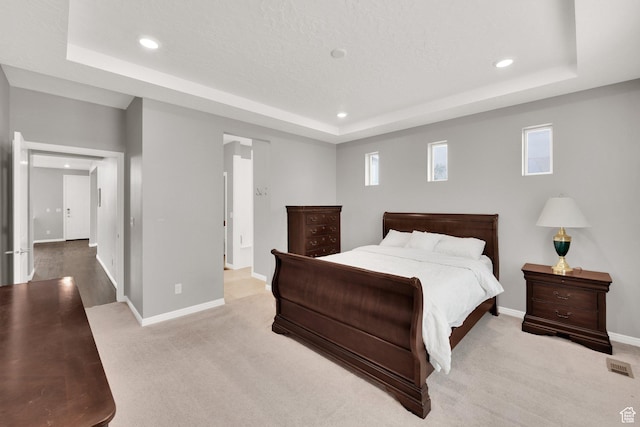 bedroom featuring a raised ceiling, baseboards, recessed lighting, and light carpet