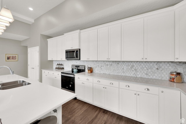 kitchen with stainless steel appliances, a sink, decorative backsplash, dark wood finished floors, and white cabinets