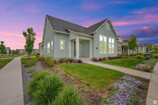 view of front of home featuring a front yard, a shingled roof, and stucco siding
