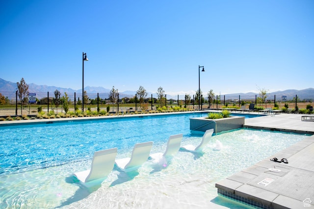 community pool featuring a mountain view, fence, and a patio area