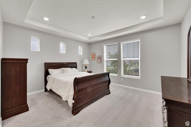 bedroom with a tray ceiling, light colored carpet, baseboards, a textured ceiling, and recessed lighting