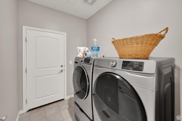 washroom featuring washing machine and clothes dryer, baseboards, and light tile patterned flooring