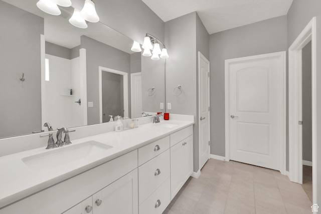bathroom with a chandelier, double vanity, and baseboards