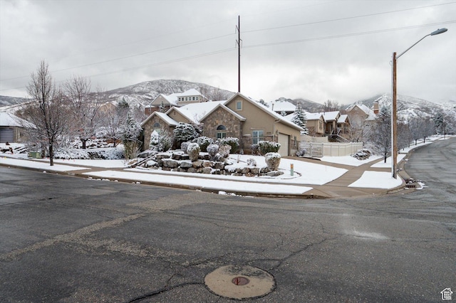 view of front of house with fence, a mountain view, a residential view, concrete driveway, and an attached garage