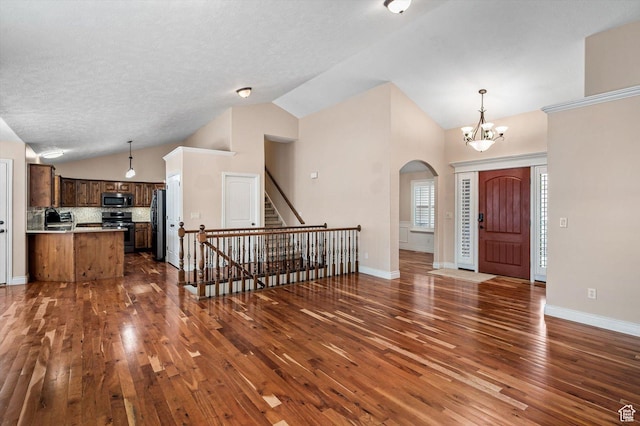 4876 S 1525 E, Ogden, UT 84403 - entryway with baseboards, lofted ceiling, arched walkways, dark wood-style flooring, and a notable chandelier