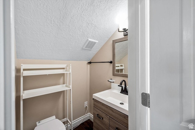 4876 S 1525 E, Ogden, UT 84403 - bathroom with visible vents, toilet, vanity, vaulted ceiling, and a textured ceiling