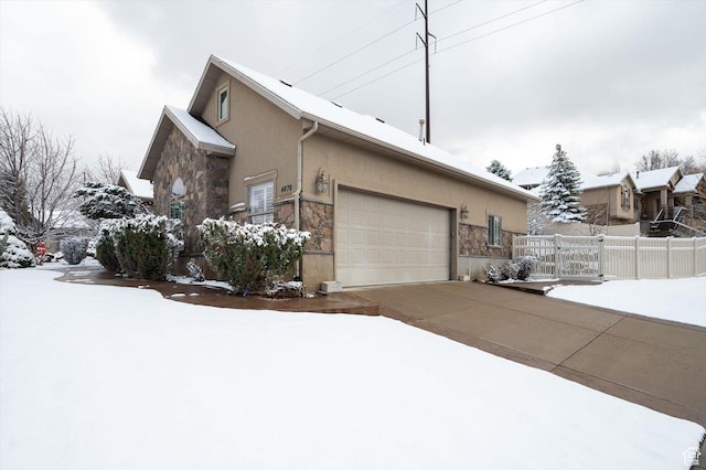 4876 S 1525 E, Ogden, UT 84403 - view of snowy exterior featuring fence, stucco siding, stone siding, driveway, and a gate