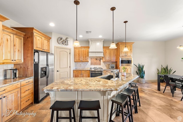 kitchen with premium range hood, stainless steel appliances, a kitchen island with sink, backsplash, and sink