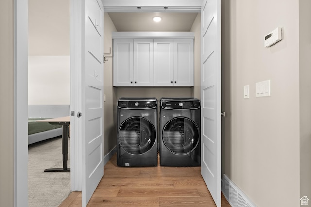 laundry area featuring light wood-style floors, cabinet space, independent washer and dryer, and visible vents