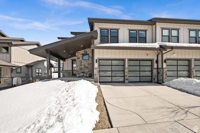 view of front of house with board and batten siding, concrete driveway, a garage, and stone siding