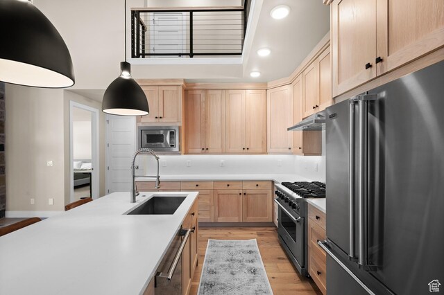 kitchen with extractor fan, high quality appliances, light brown cabinets, and a sink