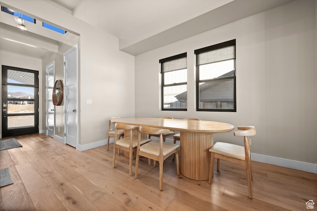 dining space with light wood finished floors, a healthy amount of sunlight, and baseboards