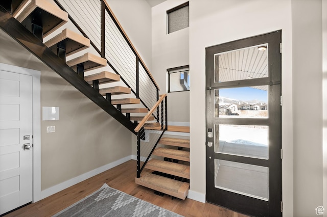 entryway with stairway, baseboards, and wood finished floors
