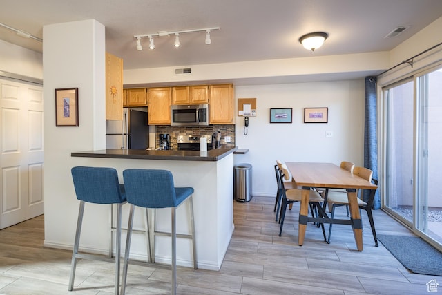 3253 E Fairway Loop, Moab, UT 84532 - kitchen with kitchen peninsula, appliances with stainless steel finishes, a kitchen bar, and decorative backsplash