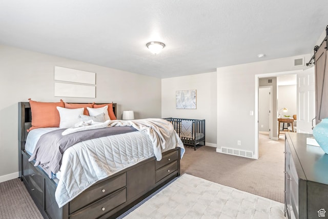 bedroom featuring a barn door, light colored carpet, visible vents, and baseboards