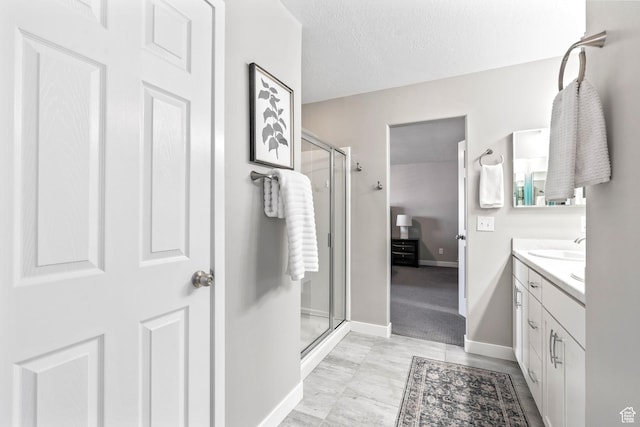 bathroom with baseboards, a textured ceiling, a stall shower, and vanity
