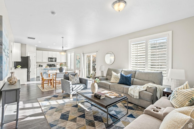 living area featuring recessed lighting, plenty of natural light, dark wood-style floors, and visible vents