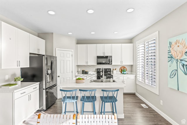 kitchen featuring light countertops, stainless steel fridge with ice dispenser, black microwave, and a sink