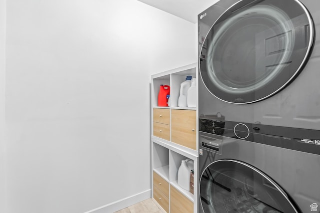 laundry room with laundry area, wood finished floors, baseboards, and stacked washer / drying machine