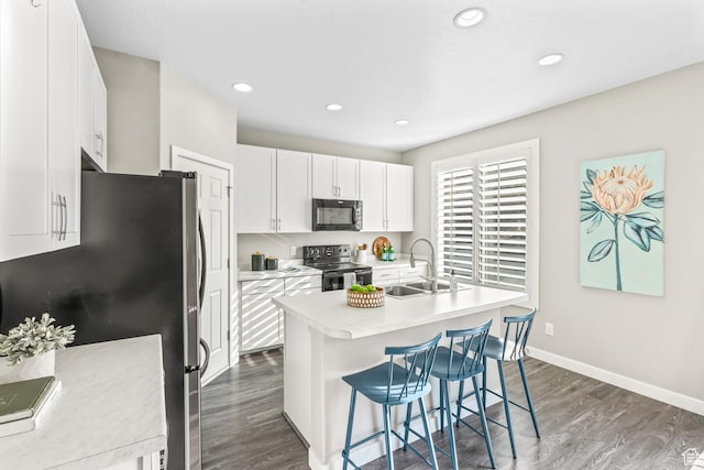 kitchen with black appliances, light countertops, dark wood-type flooring, and a sink