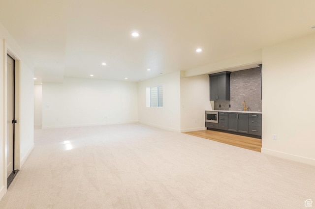 7277 W Hall Crossing Dr S, Herriman, UT 84096 - unfurnished living room featuring light carpet, recessed lighting, indoor wet bar, and a sink