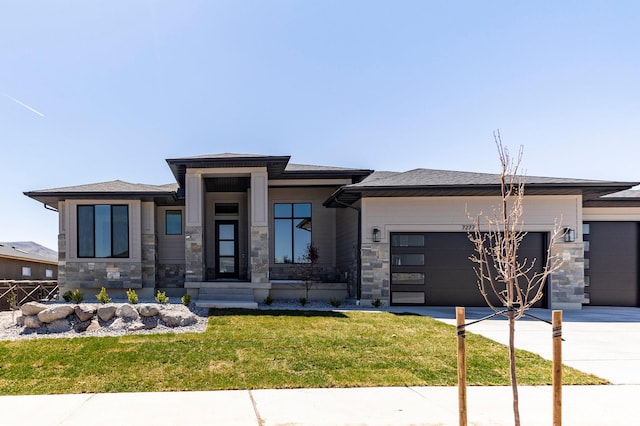 prairie-style home with a front yard, driveway, stone siding, and a garage