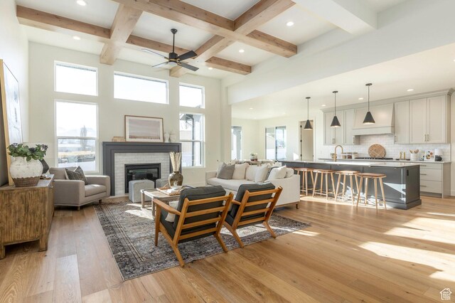 7277 W Hall Crossing Dr S, Herriman, UT 84096 - living room featuring beamed ceiling, ceiling fan, light wood finished floors, and plenty of natural light