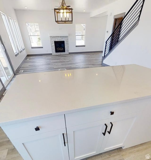 kitchen featuring white cabinetry, a notable chandelier, hanging light fixtures, and light wood-type flooring