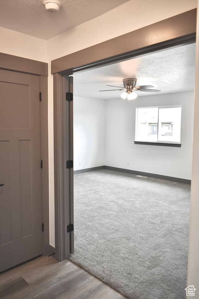 empty room with ceiling fan, a textured ceiling, and carpet flooring