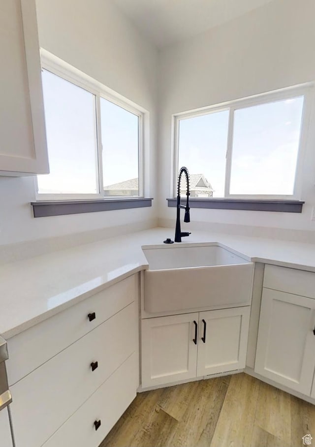 kitchen featuring white cabinetry, sink, and light wood-type flooring