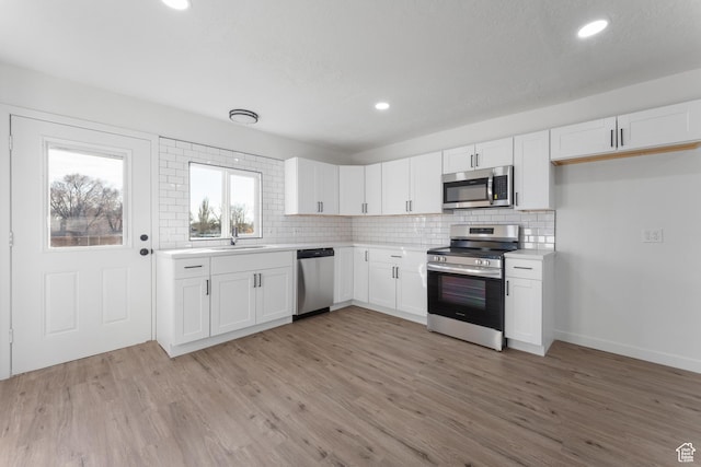 225 8th St, Ogden, UT 84404 - kitchen with stainless steel appliances, tasteful backsplash, light wood-type flooring, white cabinetry, and sink