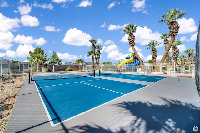 view of tennis court featuring basketball hoop and a playground