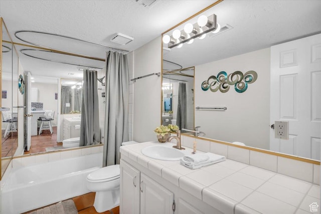 full bathroom with toilet, vanity, a textured ceiling, and shower / bath combination with curtain