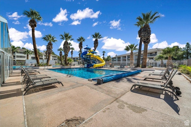 view of swimming pool featuring a water slide, a patio, and a playground