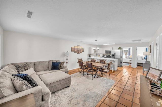 living room with a textured ceiling, a notable chandelier, and light tile patterned floors