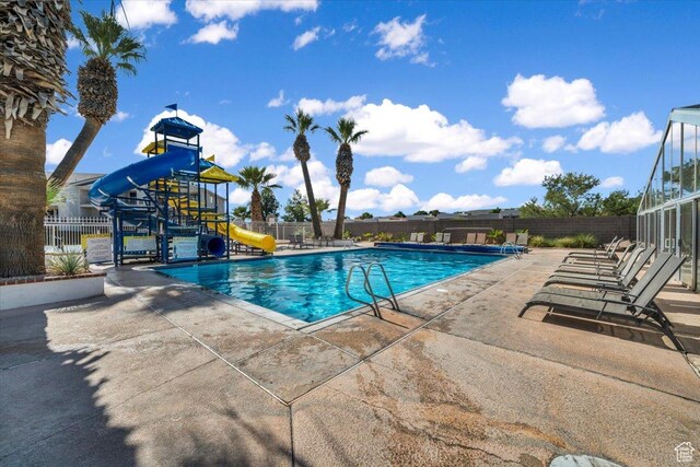 view of swimming pool featuring a playground, a patio area, and a water slide