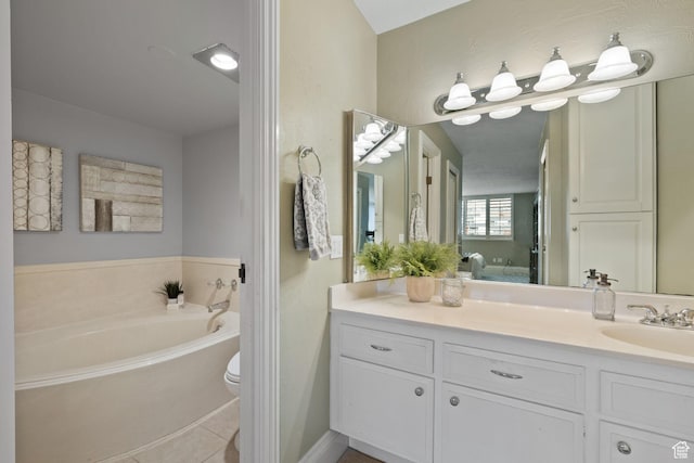 bathroom featuring toilet, vanity, tile patterned floors, and a bath