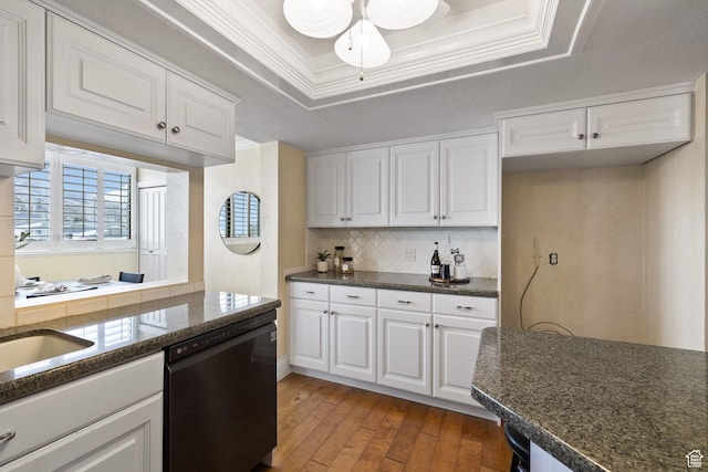 kitchen with white cabinets, dishwasher, hardwood / wood-style floors, tasteful backsplash, and a tray ceiling