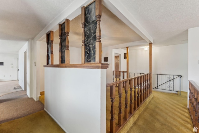 corridor with a textured ceiling and light colored carpet